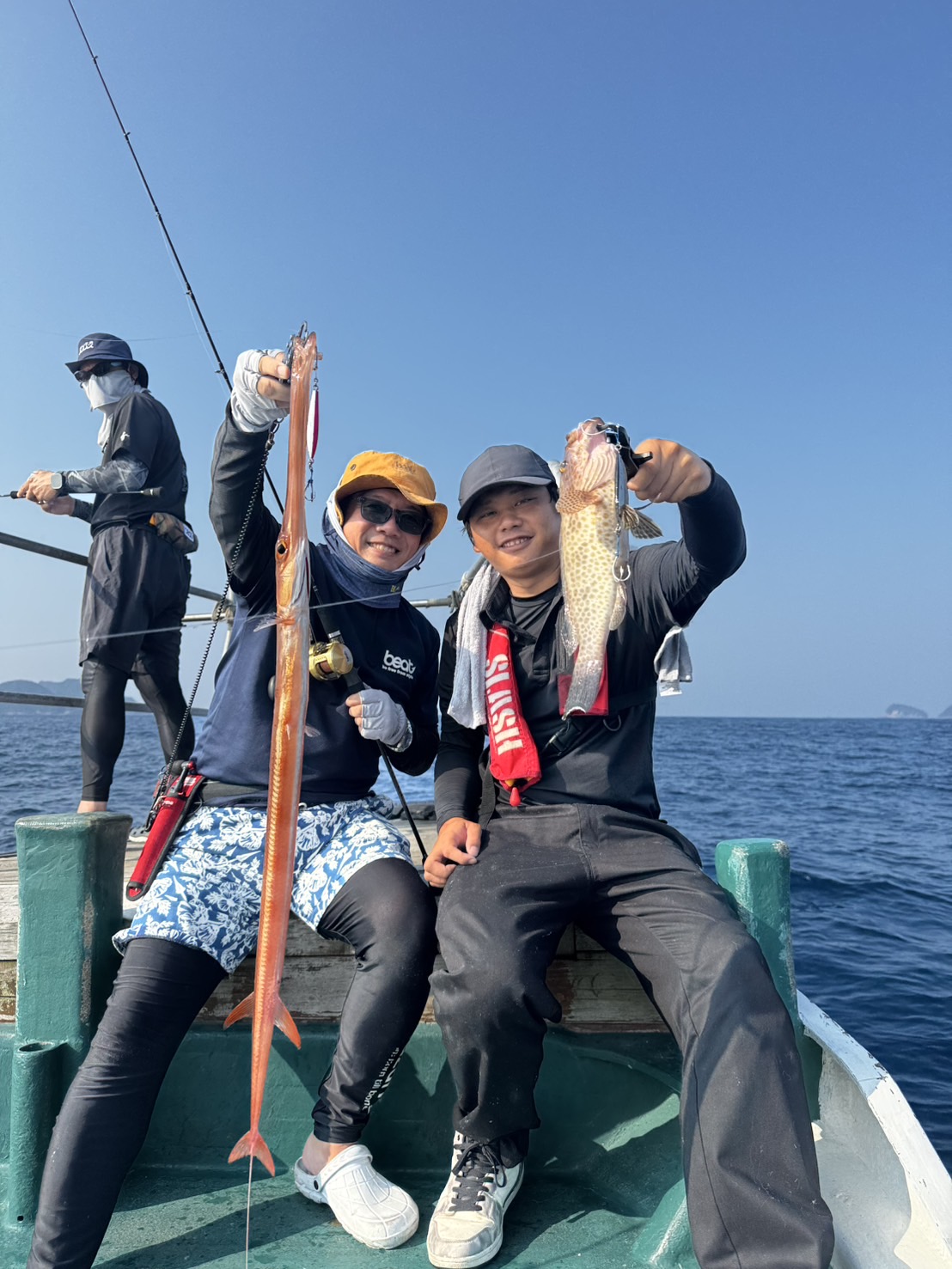 船の上で釣果を掲げた二人の人